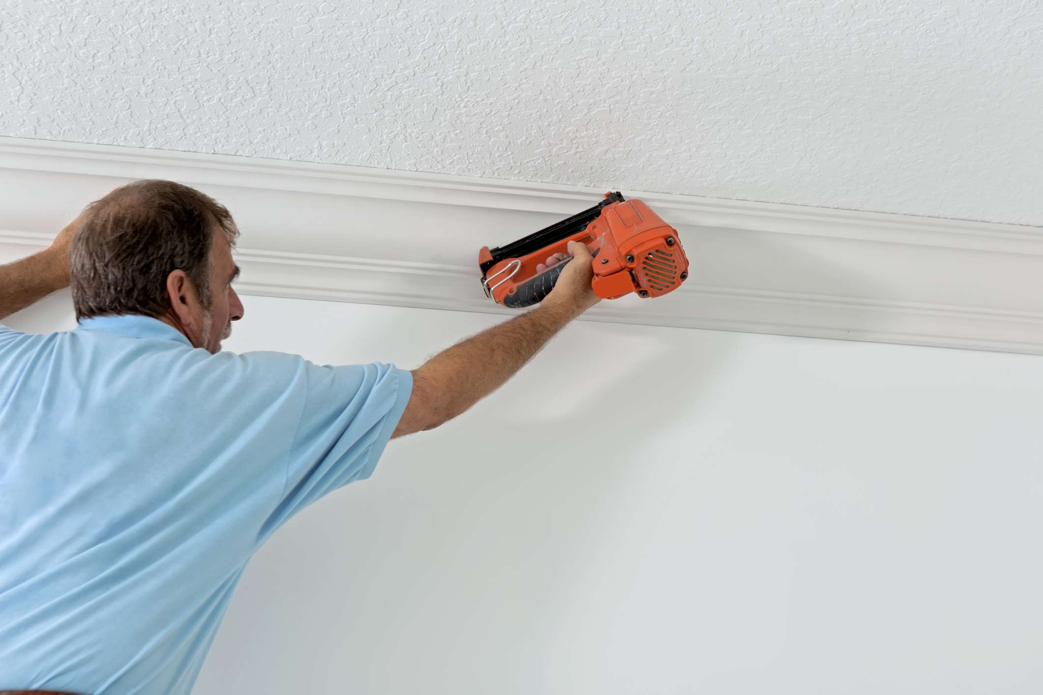 Crown molding being installed along a ceiling line in a Delaware County home