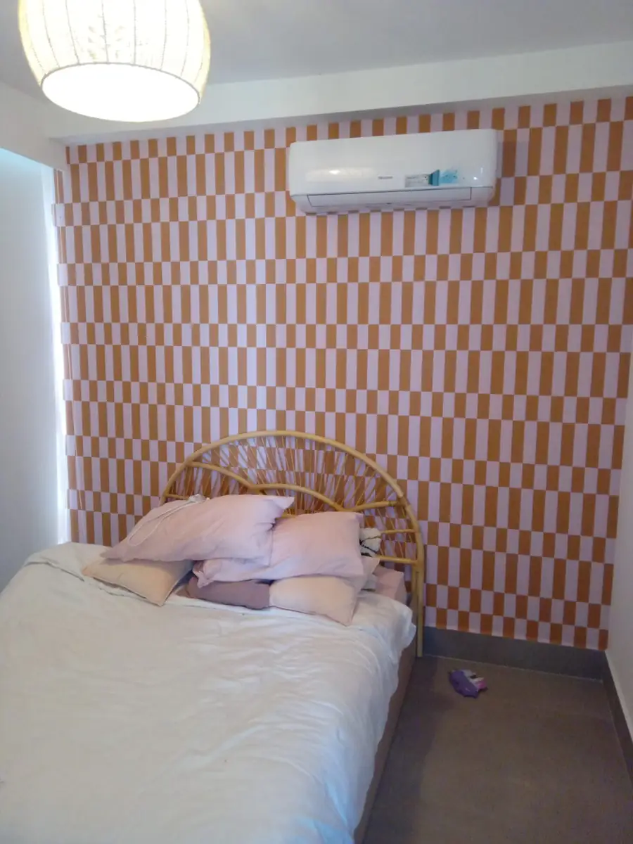 An orange and white checkerboard wallpaper behind a bed