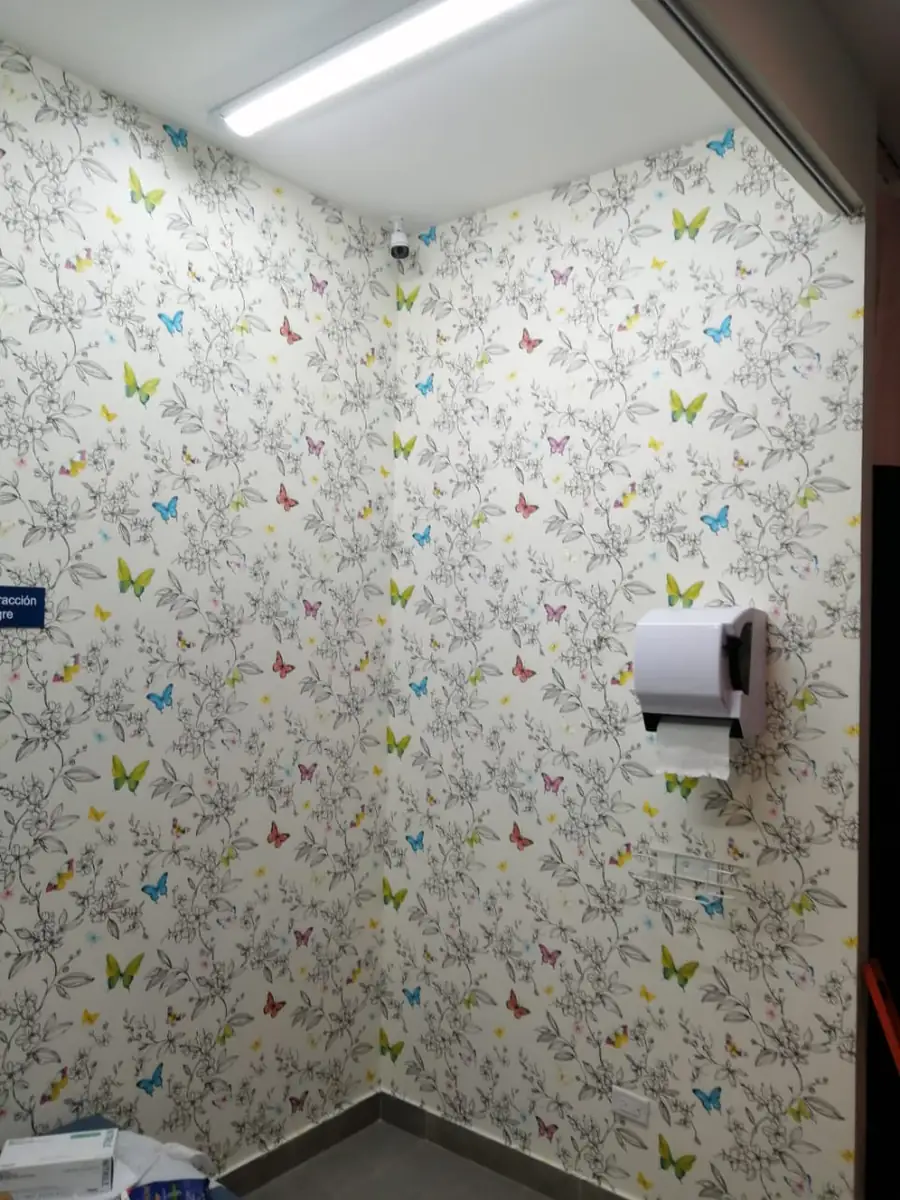 A white wallpaper printed with small colored butterflies, wrapped into a corner